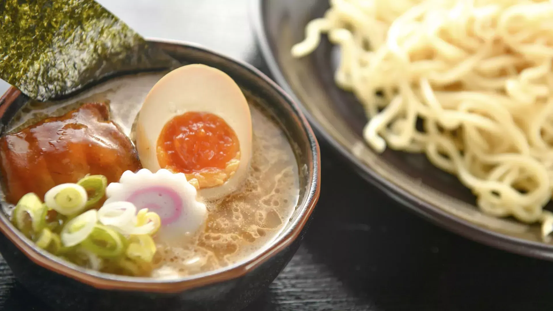 麺とラーメンスープのボウル、そして半分に切ったポーチドエッグのクローズアップショット。