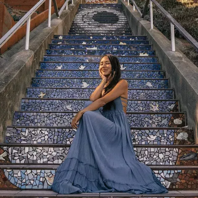 A woman poses sitting on the 16th Avenue tiled stairs in the Sunset 社区 of San Francisco.